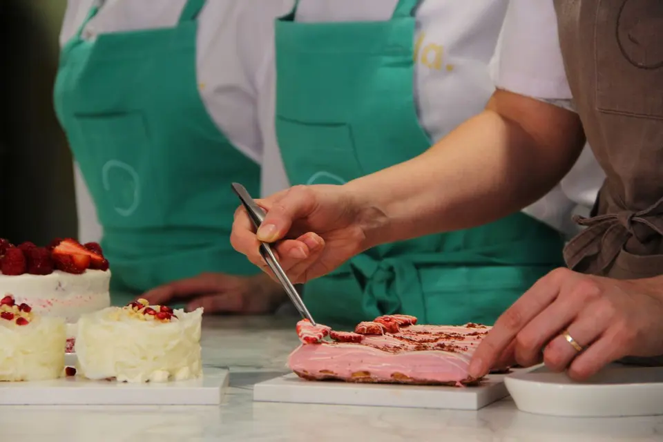 Pastelera colocando decoraciones en un postre con pinzas