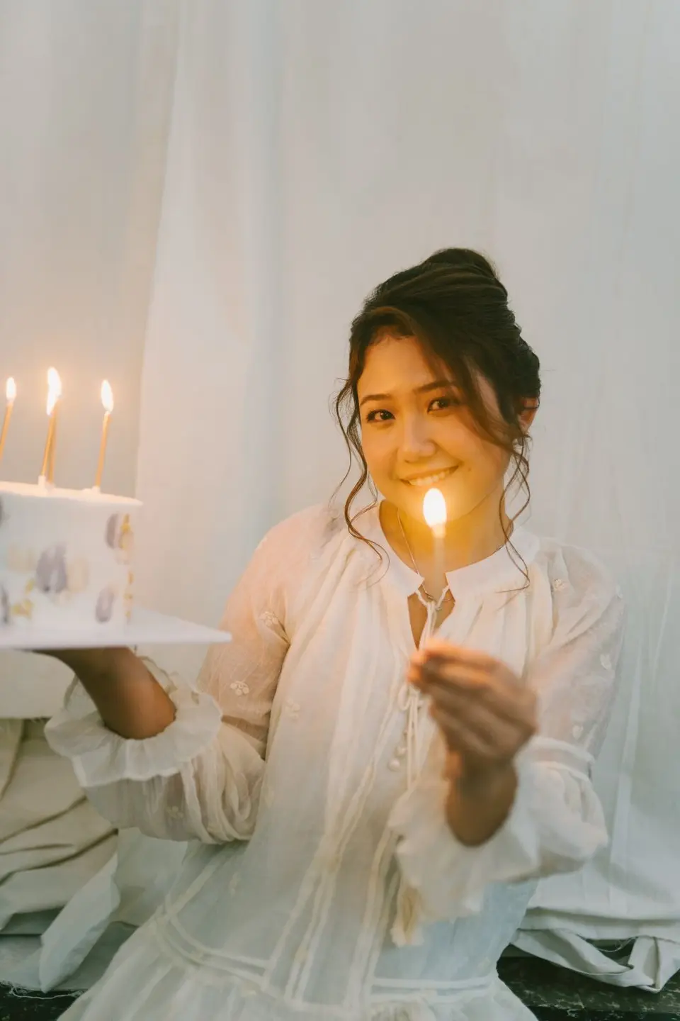 Mujer sonriente encendiendo las velas de una torta