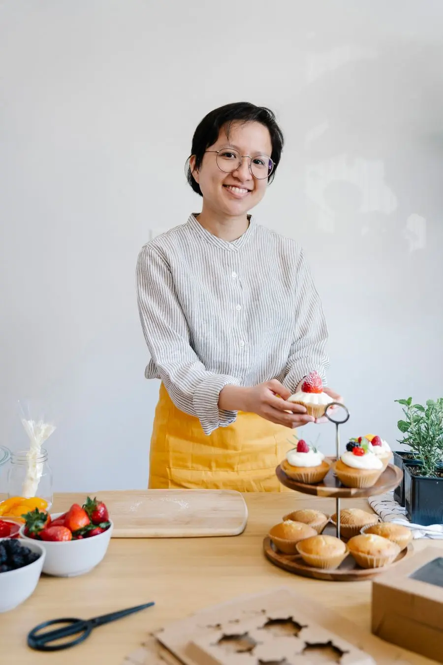 Valentina Rojas, maestra tortera y fundadora, sonriendo con una bandeja de cupcakes