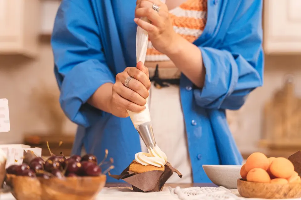 Manos decorando un cupcake con manga pastelera